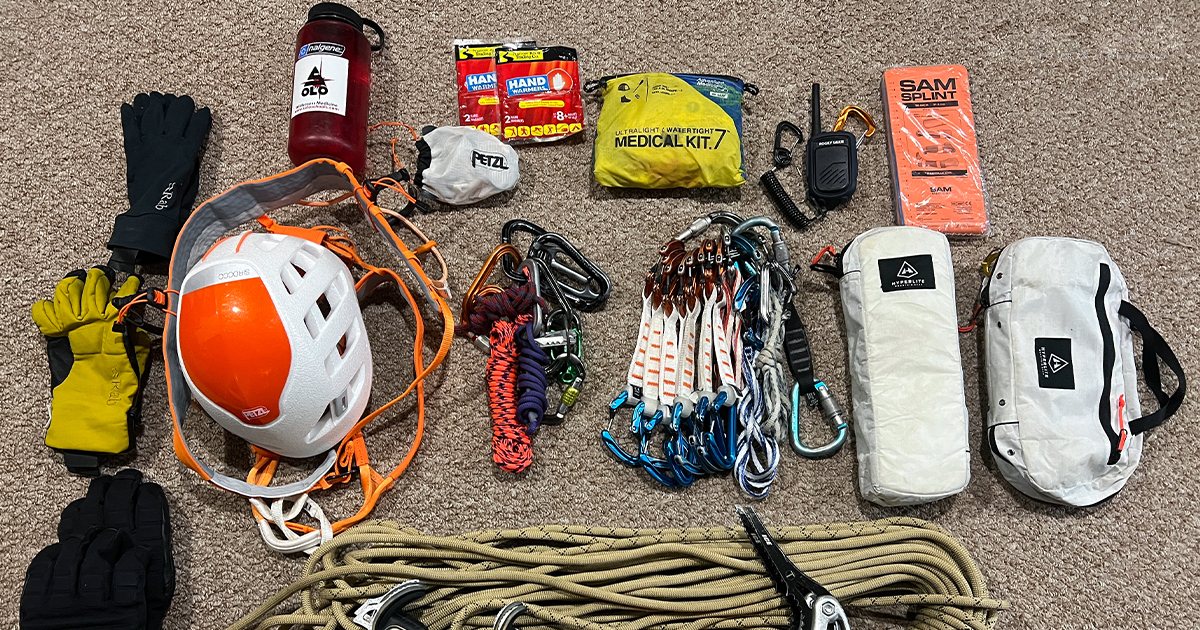 image of mountain climbing gear including gloves, water bottle, helmer, ropes, carbiner, medical kit, and walkie-talkie